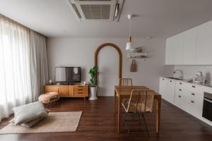 a kitchen and living room with a table and a tv at The Earth Hotel in Chiang Mai