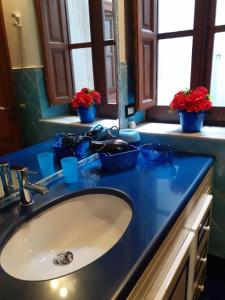 a bathroom sink with a blue counter top and flowers at Home Casa Professa 2 in Palermo
