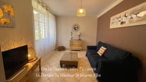 a living room with a couch and a tv at Gîte le Couradou - le domaine du viticulteur in Saint-Maurice-dʼIbie