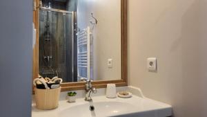 a bathroom with a sink with a mirror and a shower at La Martinoise Patio in Saint-Martin-de-Ré