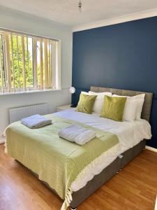 a bedroom with a large bed with a blue wall at Large 4 Bed House - 2 Bathrooms With Parking - Ipswich in Nacton