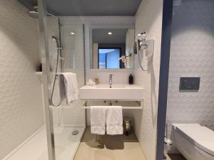 ein Bad mit einem Waschbecken, einer Dusche und einem Spiegel in der Unterkunft Mercure Hotel Delémont in Delémont