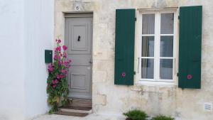 a door and a window on a building with flowers at La Martinoise Patio in Saint-Martin-de-Ré