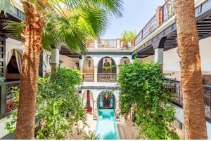 een appartementencomplex met een zwembad en palmbomen bij Riad Espoir, Riad de charme en exclusivité dans la médina de Marrakech in Marrakesh