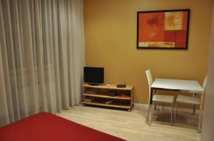 Cette chambre dispose d'une table et d'un bureau avec une télévision. dans l'établissement Les Studios De La Place (Part-Dieu), à Lyon