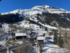 uma aldeia coberta de neve em frente a uma montanha em Appartement en plein centre du village (6-8 personnes) em Les Contamines-Montjoie