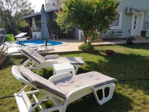 a group of lounge chairs sitting in the grass near a pool at Chillout Apartments with Pool Patricia in Fažana