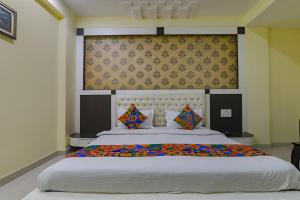 una camera da letto con un grande letto bianco con cuscini colorati di FabHotel Govinda Royal a Kānpur
