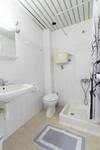 a white bathroom with a sink and a toilet at Kantaros Apartments in Ýpsos