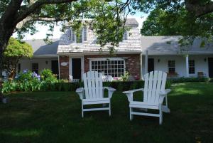 two white chairs and a table in front of a house at Chatham Seafarer Inn in Chatham