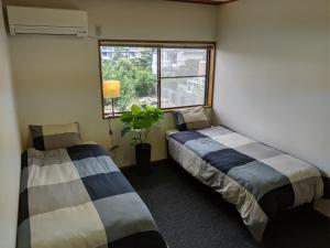 two beds in a room with a window and a plant at roundabout TOYONAKA in Toyonaka