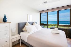 a bedroom with a bed with a view of the ocean at Azure Absolute Beachfront I Pet Friendly in Callala Beach