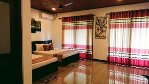 1 dormitorio con 2 camas y cortinas rojas y blancas en Mihisara Resort en Anuradhapura