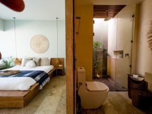 a bedroom with a bed and a bathroom with a shower at Kai Villas Lombok in Kuta Lombok