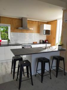een keuken met een groot eiland met vier krukken bij Relax in Kenmure in Dunedin