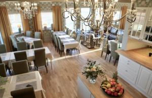 a dining room with tables and chairs and a chandelier at Torpa Gård in Borensberg
