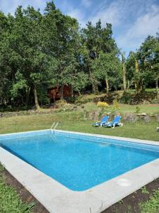 a swimming pool in a yard with two chairs at Veiga Mariña in A Xesteira