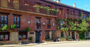 un edificio de ladrillo rojo con plantas en los balcones en El Rodeno de Gea Ideal parejas, en Gea de Albarracín