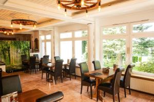 a dining room with tables and chairs and windows at Waldgasthaus am Schwarzenbruch in Allenbach