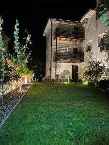 une arrière-cour de nuit avec une pelouse verte dans l'établissement Luxor Apartmani 2, à Vrnjačka Banja