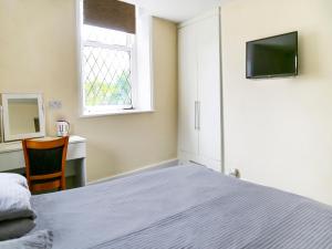 een slaapkamer met een bed, een bureau en een televisie bij OYO Castle Hotel, Accrington in Accrington