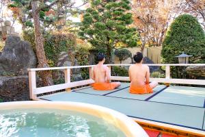 twee mannen op een tennisbaan naast een zwembad bij Kur and Hotel Shinshu in Shiojiri