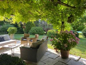 um pátio com cadeiras de vime, uma mesa e flores em Villa de Miha em Valbonne