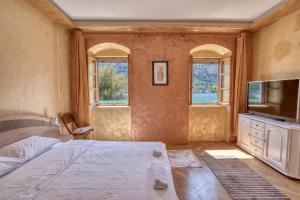 a bedroom with a bed and a tv and windows at Stone Home Kotor in Dobrota