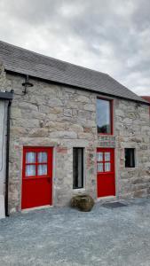 ein Steingebäude mit zwei roten Garagentüren in der Unterkunft Ballykeel Farm, Mourne Mountains in Ballymartin