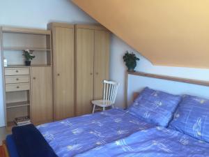 um quarto com uma cama com lençóis azuis e uma cadeira em Barátságos ház emelete em Debrecen