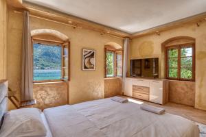 a bedroom with a bed and a tv and windows at Stone Home Kotor in Dobrota