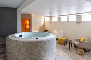 - une grande baignoire dans une pièce avec une chaise et une table dans l'établissement BEST WESTERN La Porte des Châteaux, à Meung-sur-Loire