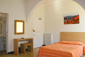 a bedroom with a bed and a table and a mirror at Hôtel Colombo- Porto Corse in Porto Ota