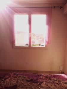 Un dormitorio con una ventana con cortinas rosas y una cama en EVANA, en Bize-Minervois