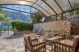 un patio con sillas y una pared de piedra. en Stone Home Kotor en Dobrota