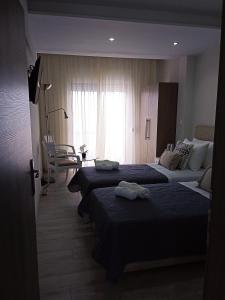 a hotel room with two beds and a window at Myrto 's sea view in Kallithea Halkidikis