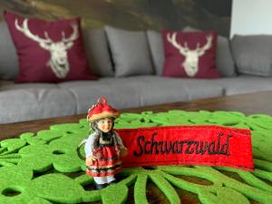 Una pequeña figura de una muñeca sentada en una mesa. en Schwarzwaldmarie, en Bühl