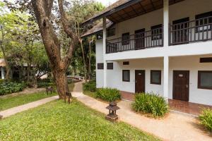 un edificio blanco con un árbol y una acera en The Legend Chiang Rai Boutique River Resort & Spa, en Chiang Rai