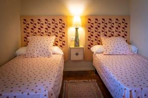 1 dormitorio con 2 camas y lámpara en Masia Can Comas, en Sant Pere de Riudebitlles