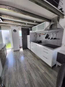 a kitchen with white cabinets and a wooden floor at Studio mezzanine Saint Bres. 20min de Montpellier in Saint-Brès