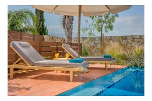 two lounge chairs and an umbrella next to a swimming pool at Yiannis Cottage in Spiliá