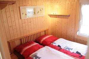 Habitación pequeña con cama con almohadas rojas en Ferienhäuser Ohratalsperre en Luisenthal