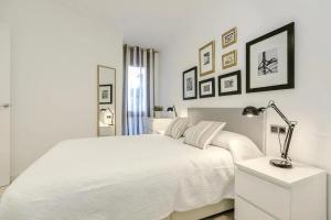 a white bedroom with a white bed and a lamp at 51SAM1021 - Modern apartment near Montjuic in Barcelona