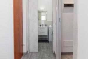 uma casa de banho branca com um lavatório e um espelho em E-Bicocca em Milão