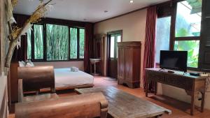 a bedroom with a bed and a desk with a television at Imah Seniman in Lembang