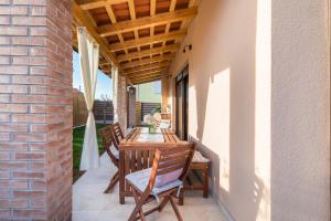 patio z drewnianym stołem i krzesłami na ganku w obiekcie Rental house Nada w Fažanie