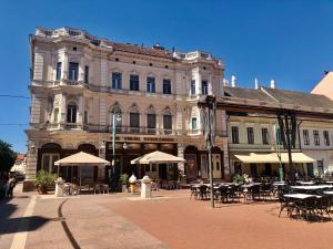 a building with tables and umbrellas in front of it at Silver Dawn Apartments in Szeged