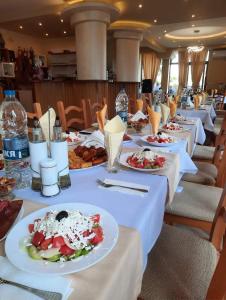 una fila de mesas con platos de comida. en Хотел-ресторант Русаков en Sandanski
