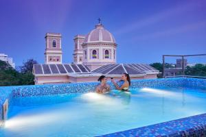 dos chicas sentadas en una piscina en un edificio en VILLA DU OCEAN en Pondicherry