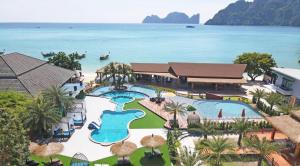 a beach scene with a pool, lawn chairs, and trees at U Rip Resort in Phi Phi Islands